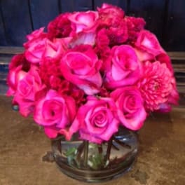Pink roses and carnations arranged in a clear glass bowl vase