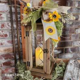 Sunflower arrangement on a wooden lantern with a candle inside