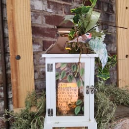 White lantern with greenery and a memorial message