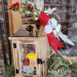 Wooden lantern with a floral spray and red ribbon accents