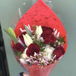 Bouquet of deep red roses and white lilies wrapped in red paper