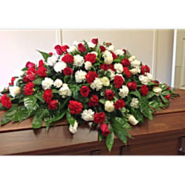 Red and white rose casket spray on a wooden casket