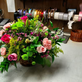 Basket arrangement of pink roses, carnations, and green mums
