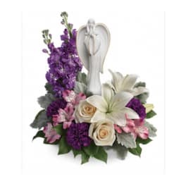 Purple and white floral arrangement with an angel figurine
