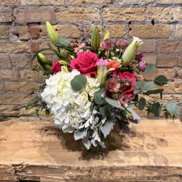 Mixed pink and peach floral arrangement in a square glass vase