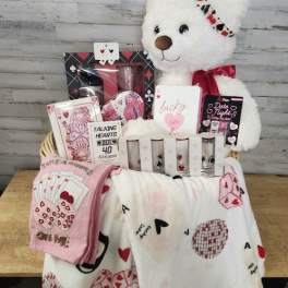 Gift basket with a teddy bear, cards, and heart-themed blankets