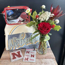 Red rose arrangement in a glass jar with a Nebraska pillow and clear zip pouch.
