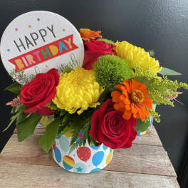 Birthday flower arrangement with roses, mums, and a greeting card topper
