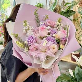Pastel bouquet of pink and lavender flowers wrapped in lilac paper