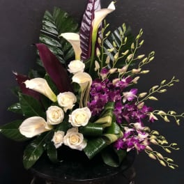Arrangement of white calla lilies, cream roses, and purple orchids