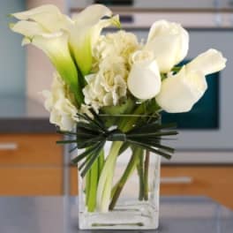 White calla lilies and hydrangeas in a clear glass vase