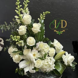 White roses and lilies arranged in a low oval centerpiece