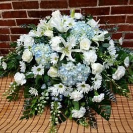 White lilies, roses, daisies, and blue hydrangeas in a low arrangement