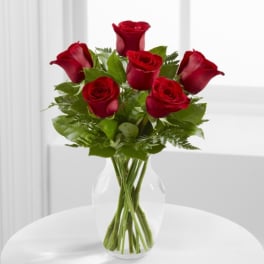 Bouquet of red roses and calla lilies in a clear glass vase