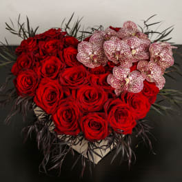 Heart-shaped arrangement of red roses with spotted orchids