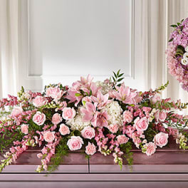 Pink floral arrangement with roses and lilies on a mantel