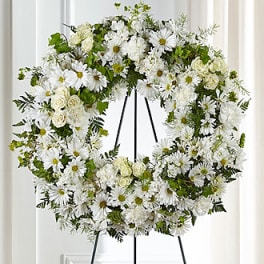 White floral wreath on a black easel stand