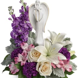 White angel figurine surrounded by purple and white flowers