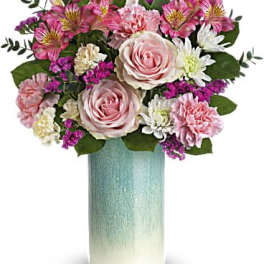 Pink roses and mixed blooms in a tall blue vase