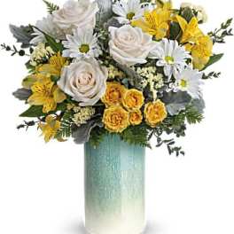 Bouquet of white and yellow flowers in a tall blue-green vase