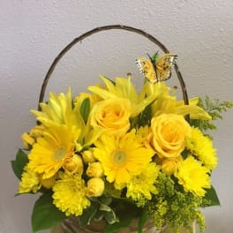 Yellow flower basket with roses, daisies, and a butterfly pick