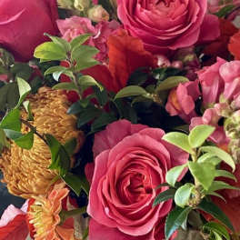 Pink roses and orange blooms arranged in a vase