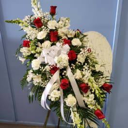 Standing floral spray with red roses and white flowers on an easel