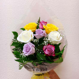 Bouquet of multicolored roses wrapped in pink paper