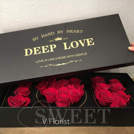 Black gift box with red roses arranged inside