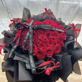 Bouquet of red roses wrapped in black paper with red ribbons