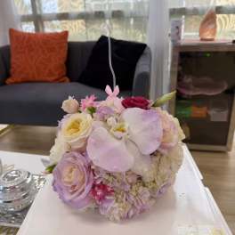 Round pastel bouquet with roses, orchids, and hydrangeas on a white box