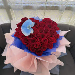 Heart-shaped bouquet of red roses with blue and pink wrapping