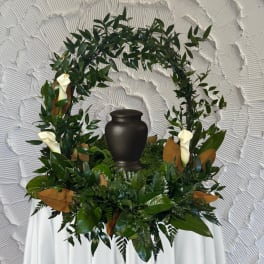 Green funeral wreath with white calla lilies around a black urn