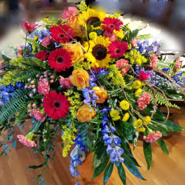 Large colorful floral arrangement with gerbera daisies, roses, and sunflowers