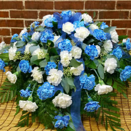 Blue and white carnation arrangement with ribbon on a woven mat