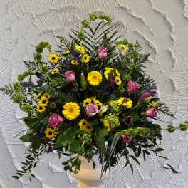 Mixed bouquet with pink roses, yellow daisies, and purple accents in a white vase