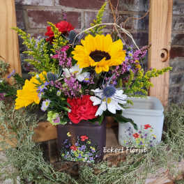 Colorful mixed flower arrangement in decorative tins with sunflowers and daisies