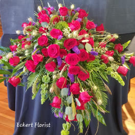 Large red rose arrangement with purple accents and mixed greenery