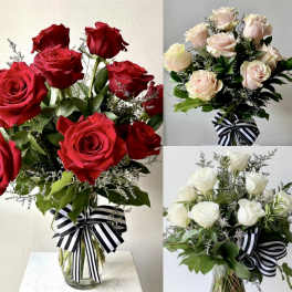 Bouquets of red, blush, and white roses in glass vases with striped ribbons