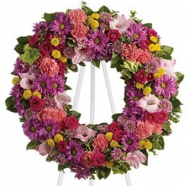Colorful floral wreath on a white stand with purple, pink, and yellow blooms