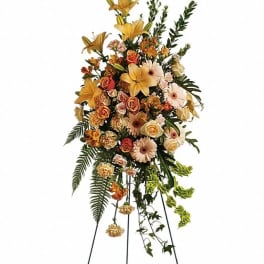 Tall standing floral spray with yellow lilies, roses, and daisies on a metal easel