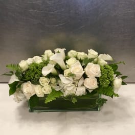 White roses and calla lilies in a low rectangular vase