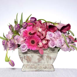 Pink and lavender floral arrangement in a decorative stone vase