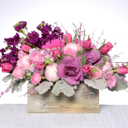Pink and purple floral arrangement in a wooden box