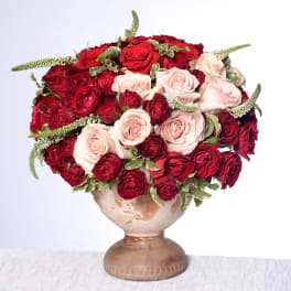 Red and blush roses arranged in a ceramic vase