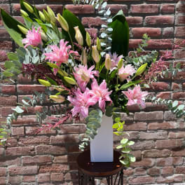 Pink lilies in a white vase with eucalyptus and greenery