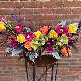 Bright mixed floral arrangement with roses and orchids on a small table