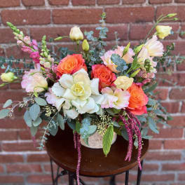 Mixed bouquet of coral and white flowers with eucalyptus in a vase
