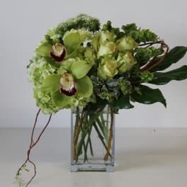 Green orchid and rose arrangement with hydrangeas in a clear rectangular glass vase
