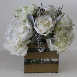 White roses and hydrangeas arranged in a square glass vase
